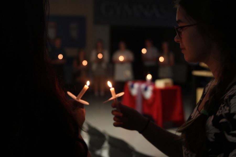 During the French National Honors Society induction ceremony on Thursday, Oct. 4, junior Joan Downey lights the candle of the person next to her. “I love the sound of French. I love French culture. I love reading books in French.”