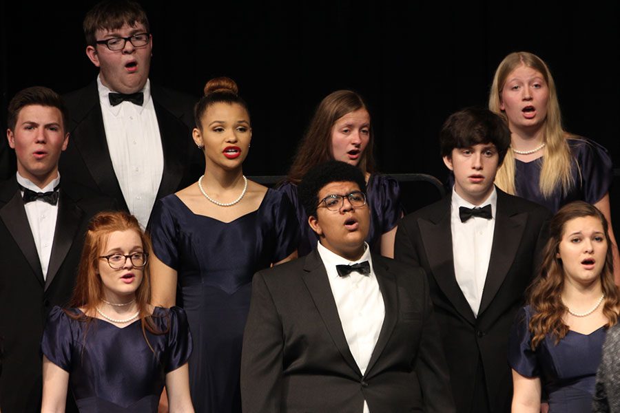 On stage in the theatre, Jag Singers prepare to sing “Safe With Me” by Bryan Sharpe.