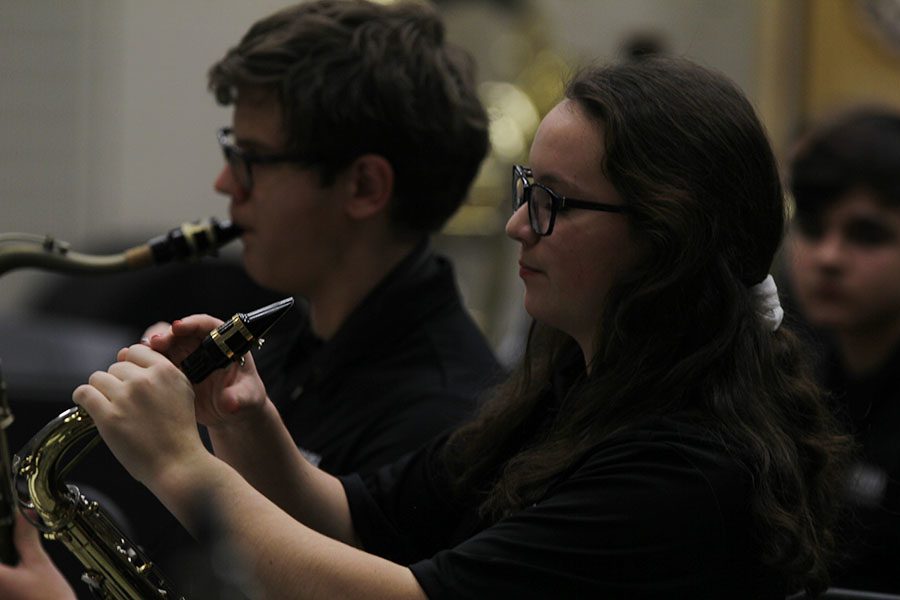 As the band prepares for performance, junior Kayla Middaugh adjusts the mouthpiece of her alto saxophone.