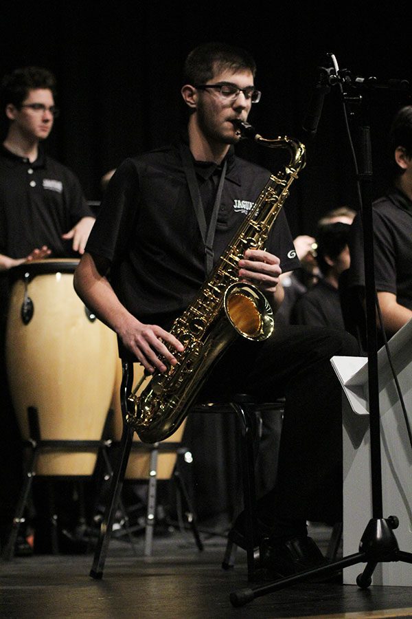 Blowing air through his tenor saxophone, junior Adam Tilden stays on beat along with the rest of the band.