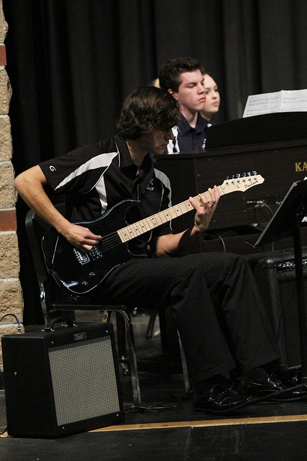 Playing his guitar, junior Justin Deas keeps his eyes on his sheet music as he keeps up with the rest of the performers.