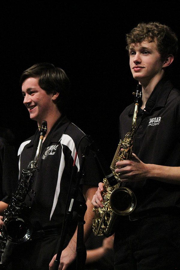 As the audience applauds them, junior saxophonist Joey Gillette and sophomore saxophonist John Fraka stand with their fellow performers and smile at the audience.