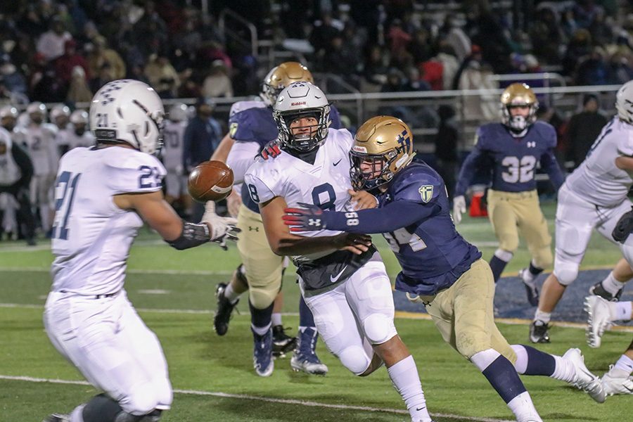 While a Saint Thomas Aquinas player comes to tackle him, senior quarterback Jordan Preston throws the ball to junior running back Tyler Green on Friday, Nov. 9. 