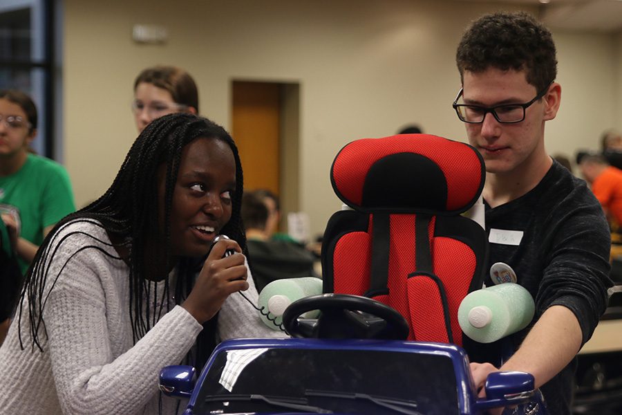 Placing the final touches on their car, sophomore Courtney Mahugu tests the microphone, and senior Tyler Hilk starts the car.