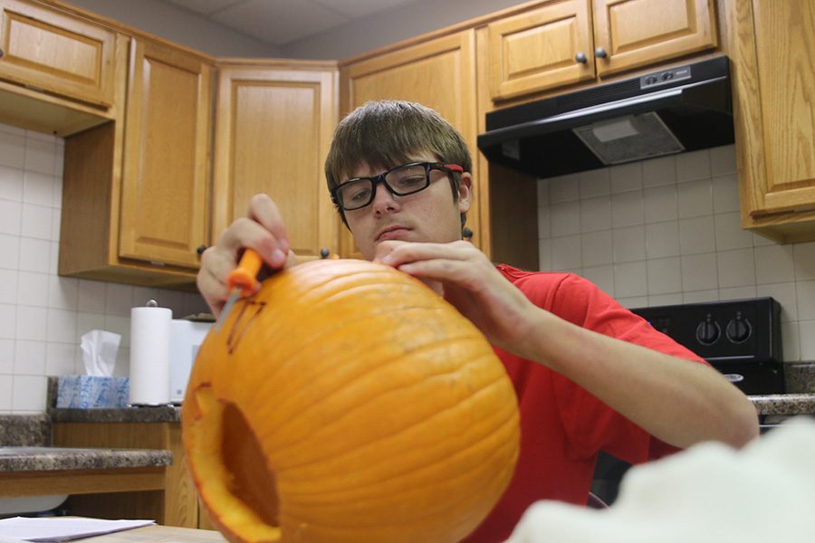 Looking down at his emptied pumpkin, Bridge student Kyle Ray prepares for Halloween festivities by carving a face into the pumpkin at the Bridge on Wednesday, Oct. 31.   
