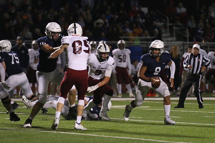 Breaking free from the pack, senior quarterback Jordan Preston looks over his shoulder for an opening in the SJA defensive line.