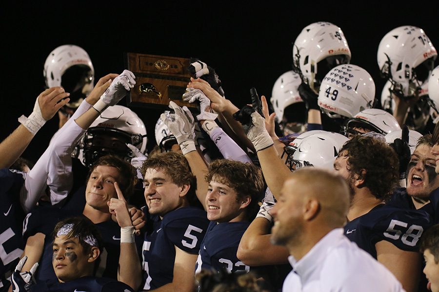 Raising their helmets in the air, the team celebrates the win with the regional trophy.