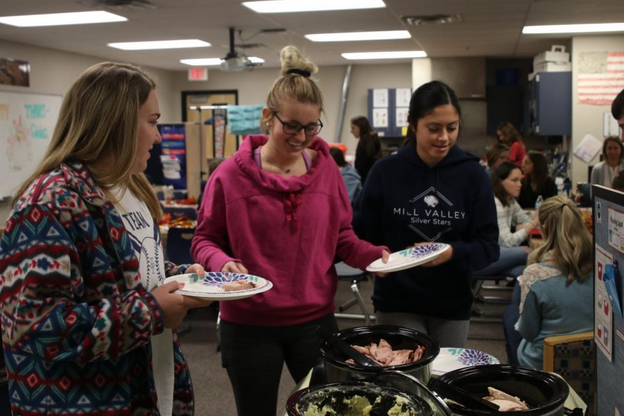 During the Peers in Learning Thanksgiving meal on Tuesday, Nov. 20, junior Paige Oliver peers over the crockpots of food. “My favorite part [of the Peers Thanksgiving] is to celebrate with all of the peers and having great food,” Oliver said. “I love being in Peers in Learning because, no matter what, my peers always find a way to put me in a good mood. Working with the students makes me feel good that I’m helping [out in our community].”
