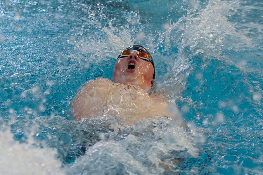 After making a turn, junior Logan Myers looks up towards the ceiling while swimming the 200-yard backstroke.