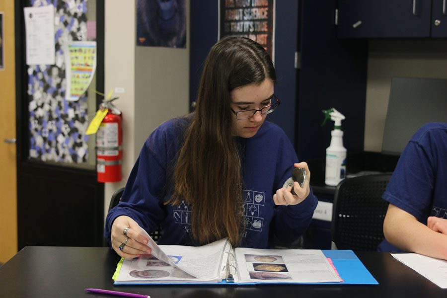 Trying to identify a fossil, junior Joan Downey compares the fossil to her notes.