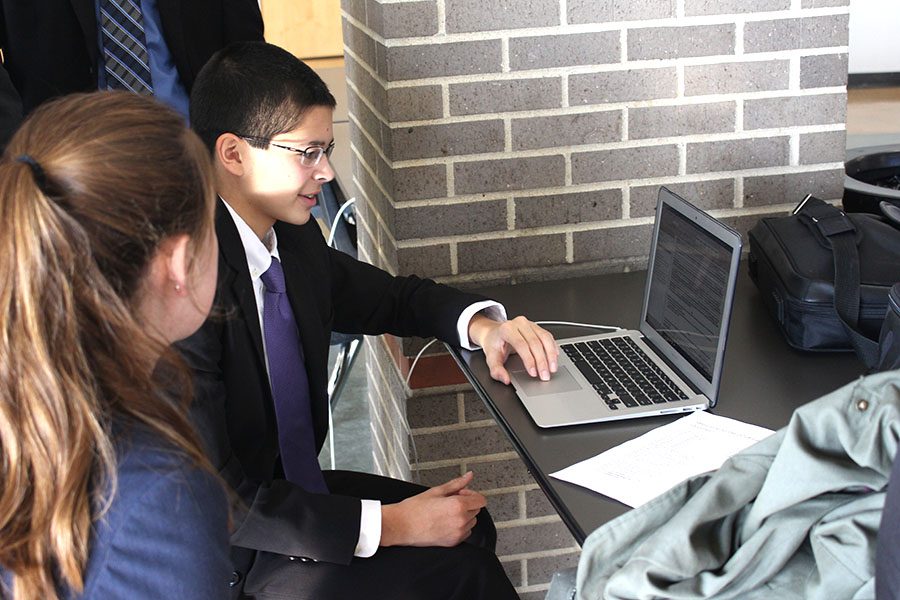 Sharing a strategy with a fellow teammate, sophomore Adam White who won 4-2, points to notes pulled up on his computer. 
