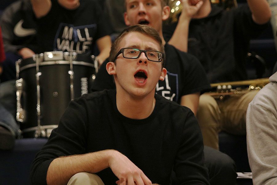 Sitting in the band section, senior Logan Arnold cheers for the basketball team against Lansing High School on Tuesday, Jan. 15.