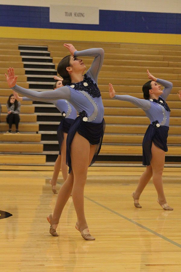 In sync with the rest of the team, freshman Anna Brazil looks toward the ceiling as she places her arms on her head.