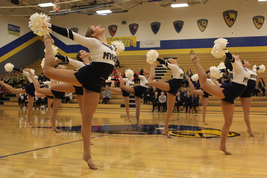Junior Sydney Ebner stands on her toes with her arms thrown back during the teams pom routine on Monday, Jan. 21.