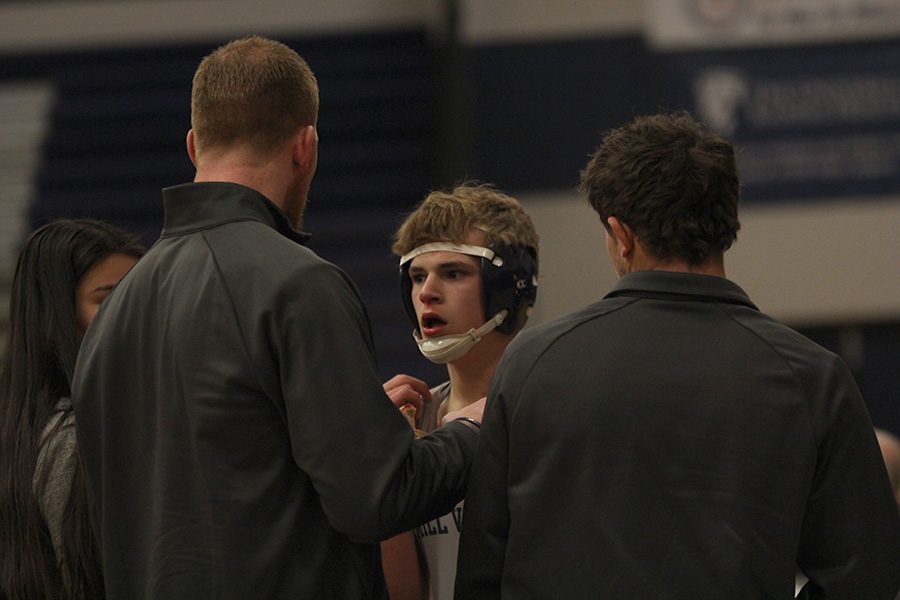 Taking a pause during his match, sophomore Dalton Harvey gets a bloody nose fixed while his coach gives him tips to finish the match with a win.