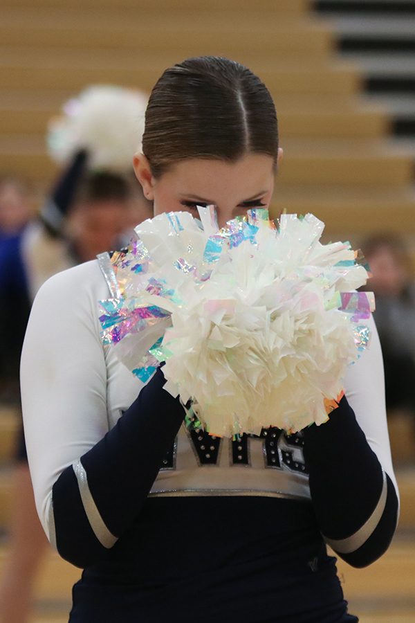 Before the pom routine, sophomore Kenzie Harris looks down into her pom’s. 