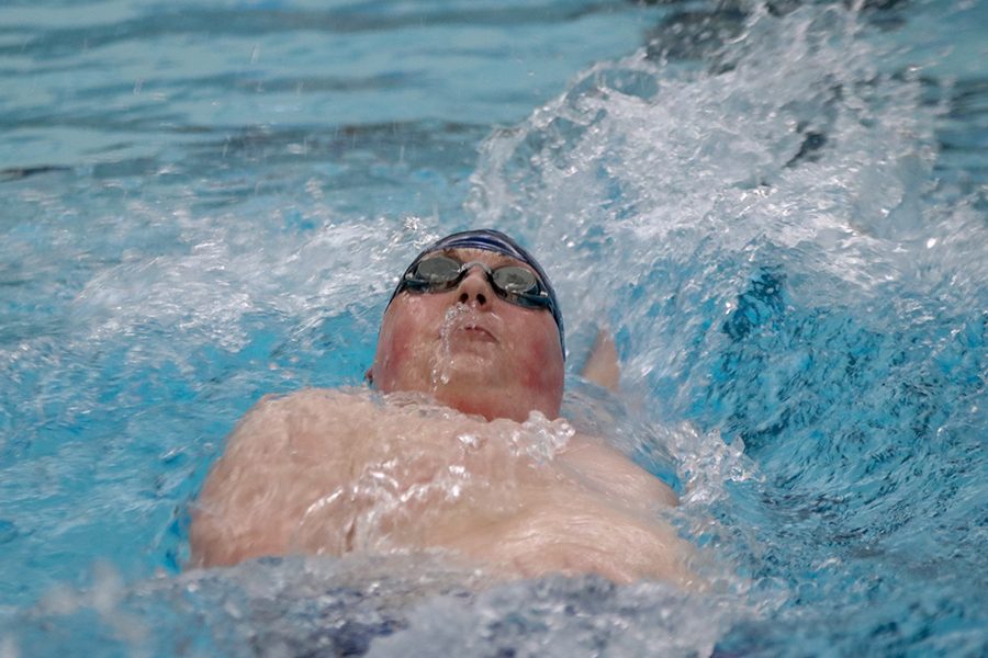 After completing a turn, junior Logan Myers looks up towards the ceiling as he competes in the backstroke. 