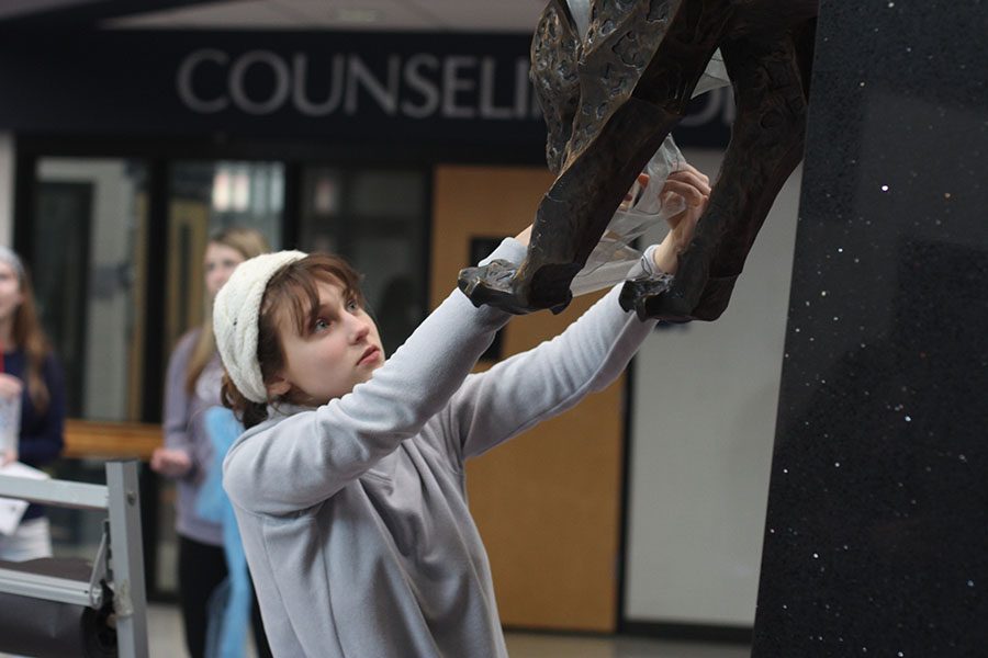 Looking up at the jaguar statue, junior StuCo member Avery Altman ties a scarf around the neck of the statue, “I think [decorating] gets people excited,” Altman said. “[Decorations] get people more into what’s going on and makes coming to school each day a little bit more fun.”