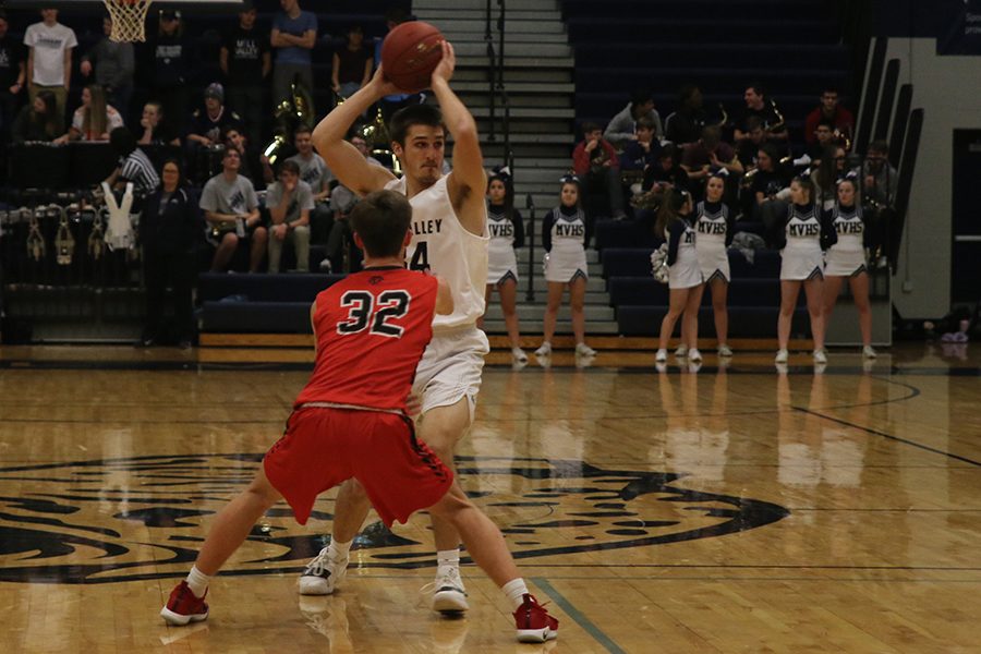 Looking under his arm, senior James Smith searches the court for an open team member.