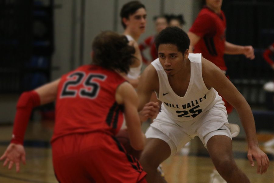 Staring down his opponent, senior Seth Hobson defends the basketball goal.