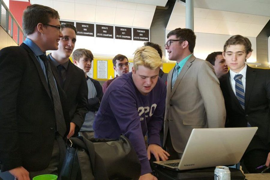 As he pulls up documents on the laptop, Debate assistant coach and alumni Jack Booth helps the team prepare for the second round. 