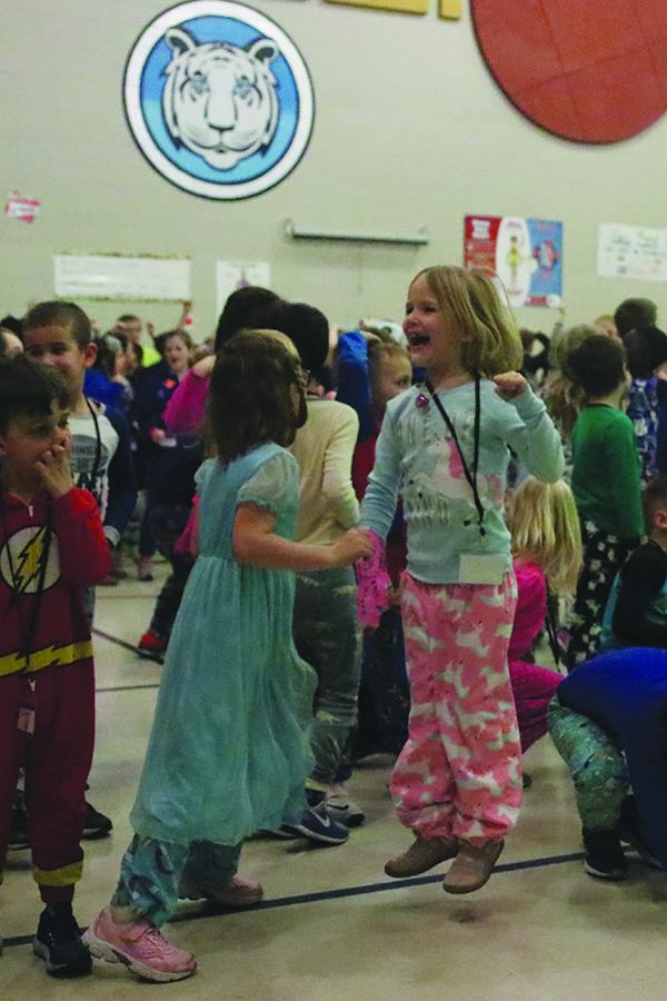 Celebrating a coin landing on heads, two elementary school students jump up and down before the next round.