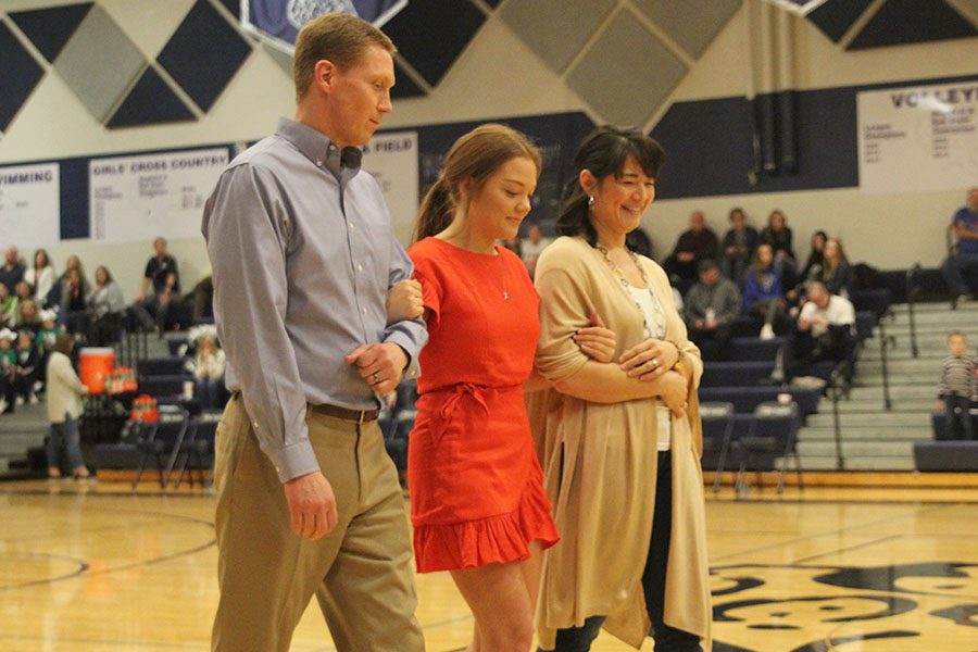 Arms linked with her parents, senior WOCO candidate Lauren Harris walks towards center court as her name is called.