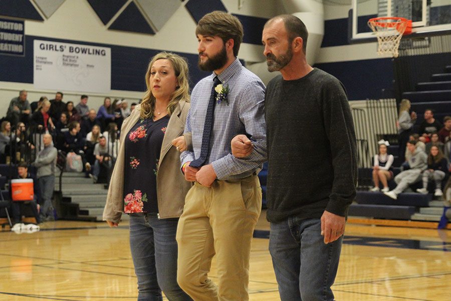 Accompanied by both parents, senior Ethan Koepke makes his way to his partner, senior Claire Kaifes.