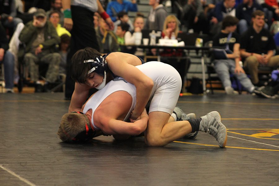 Holding opponent down, sophomore Liam Sutton locks his arms around a Olathe West wrestler.