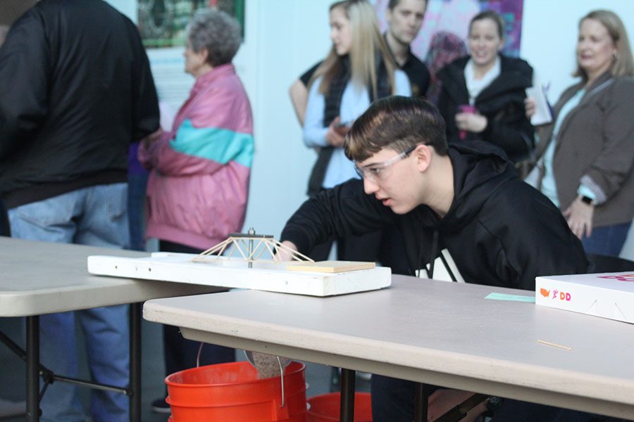 Trying to evenly distribute the weight, senior Johannes Seberger pours sand into the bucket.