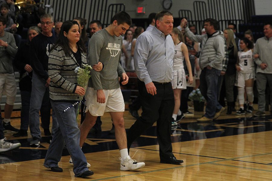 As he is introduced for senior night, senior James Smith walks out with his parents.