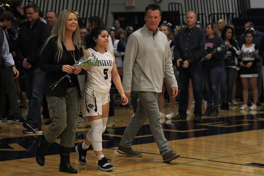 As she is introduced for senior night, senior Presley Barton walks out with her parents.