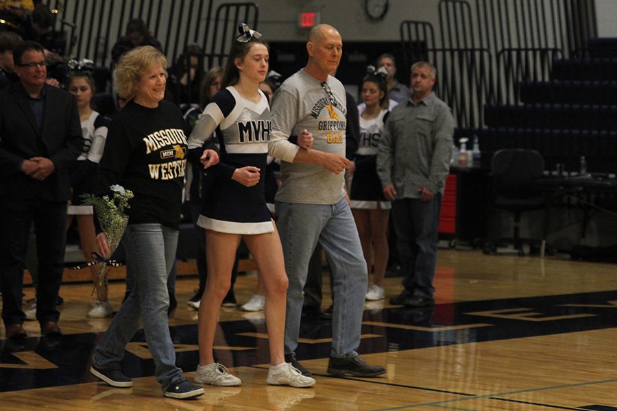 As she is introduced for senior night, senior Erin Miller walks out with her parents.