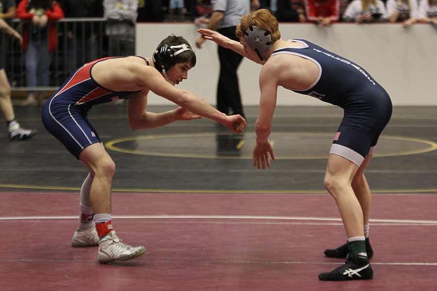 Facing his opponent, sophomore Carson Dulitz reaches for his head.