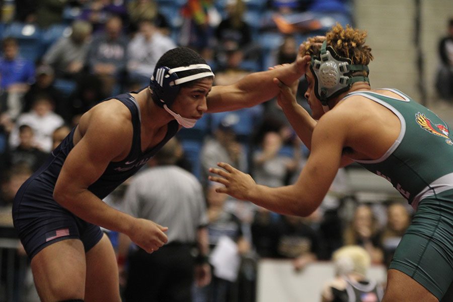 Facing his opponent, junior Tyler Green reaches to touch his head.