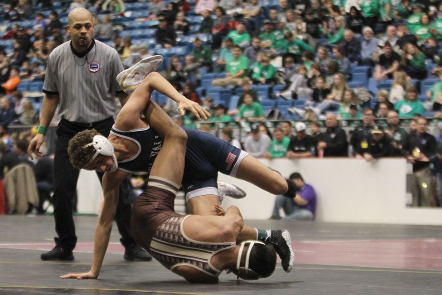 Trapped between his opponents legs, junior Zach Keal tries to avoid being taken down.