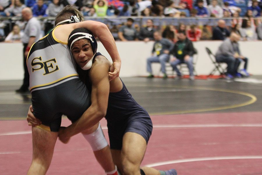 With his arms around his opponents legs, junior Tyler Green shoves him to the ground.