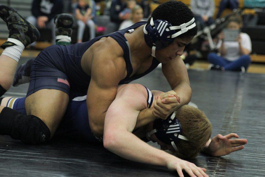 Locking his hands together and pressing down on his opponents head, junior Tyler Green pins the contestant to the ground.