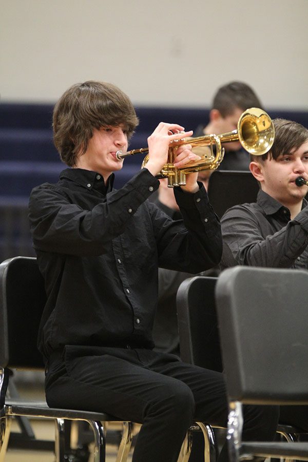 Holding his trumpet high in the air sophomore Josh Sitchler performs at the band concert.