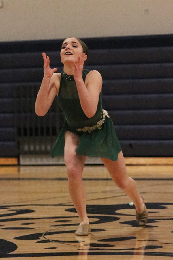 Reaching her hands up, freshman Anna Brazil performs her solo at the spring show on Saturday, March 30.