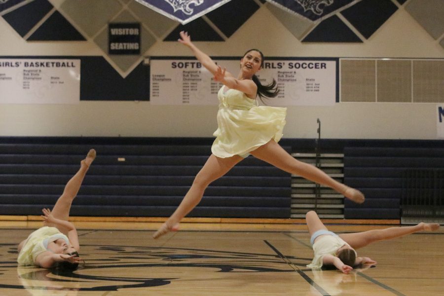 During the junior ensemble, junior Ali Greenhalgh leaps above juniors Sammie Pennington and Sydney Ebner.