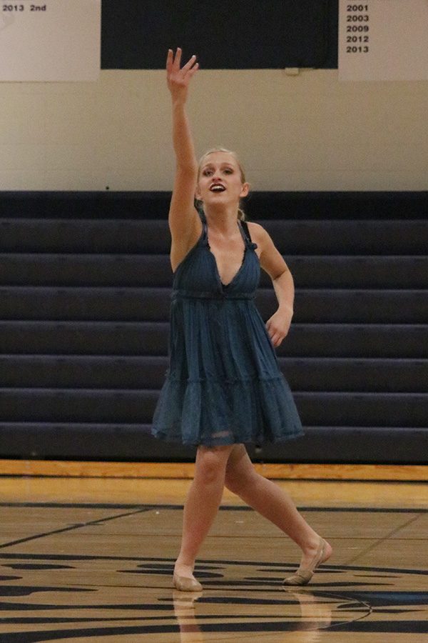 Reaching her arm up, senior Bella Line performs her solo on Saturday, March 30.