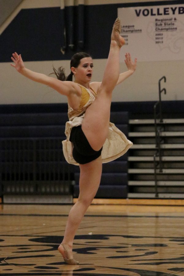 Throwing her arms out, senior Olivia Augustine performs her self-choreographed solo on Saturday, March 30.