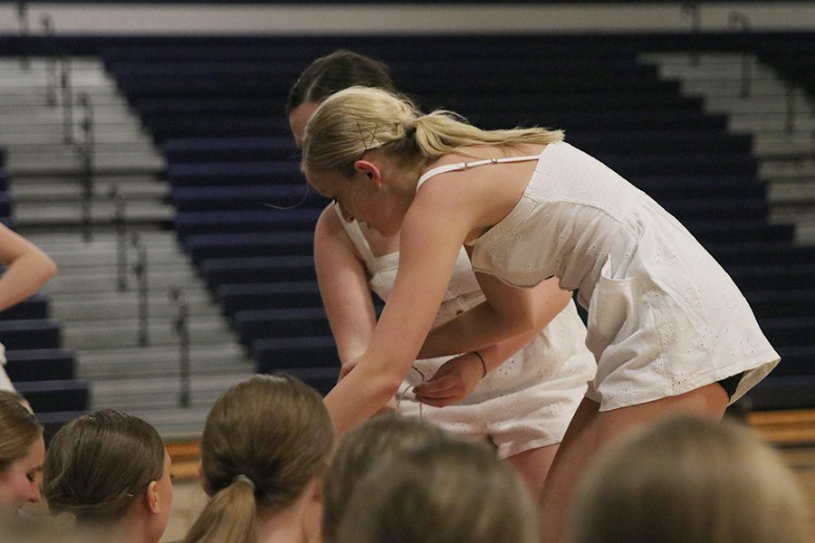 During the senior ensemble, seniors Bella Line and Eve Steinle pass out gifts to team members seated on the sideline.