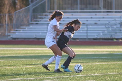 With an Olathe West player on her back, sophomore Peyton Wagoner keeps possession of the ball in the game on Thursday, March 21. The Jags won the game with a final score of 1-0. “[Olathe West] passed in patterns and we were struggling to figure out the patterns,” Wagoner said, “but once we figured it out [the game] was a lot better.”