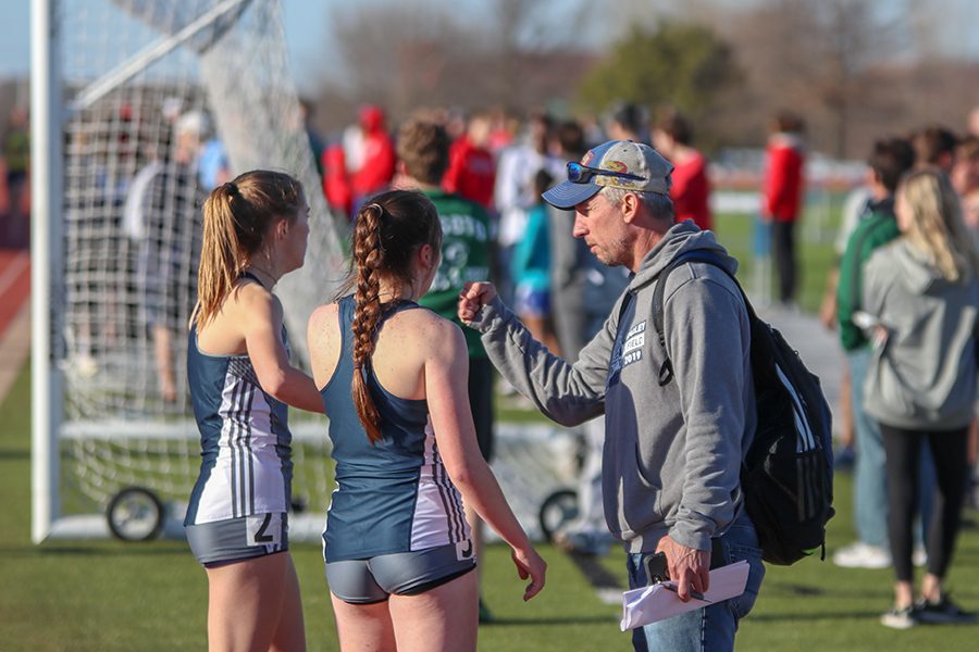 After finishing the 800-meter run, junior Molly Haymaker and senior Delaney Kemp give a fist bump to track head coach Chris McAfee. 