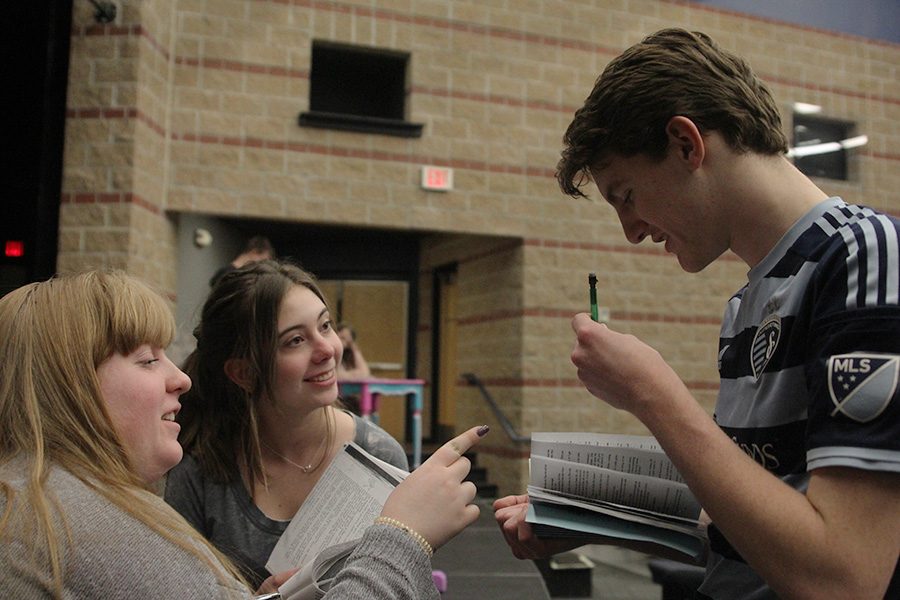 Looking over his script, sophomore Michael Brown receives notes from student directors sophomore Claire Burke and junior Chloe Griffin. 