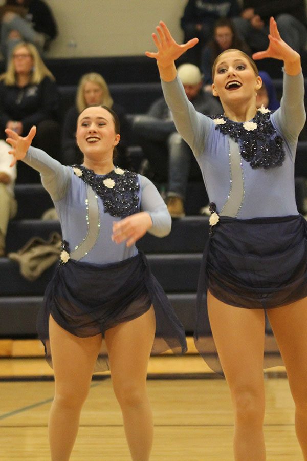 With arms reached out and expressive faces, seniors Eve Steinle and Addie Ward perform their routine at halftime of the girls basketball game on Thursday, Feb. 28.