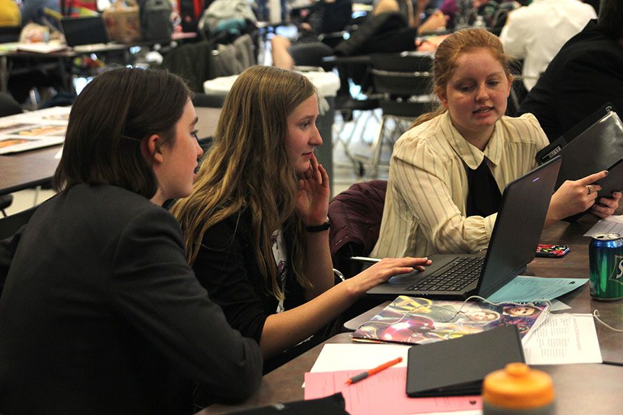 Collaborating with other team members, freshman Summer Anderson prepares before the next round.