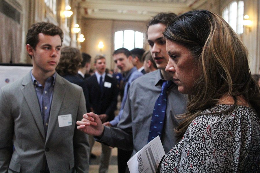 Motioning toward the poster board, senior Cameron Sizemore presents his and seniors Charlie McGraw’s senior project.